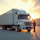 Camion semitrailer blanc neuf au lever du soleil devant un entrepôt